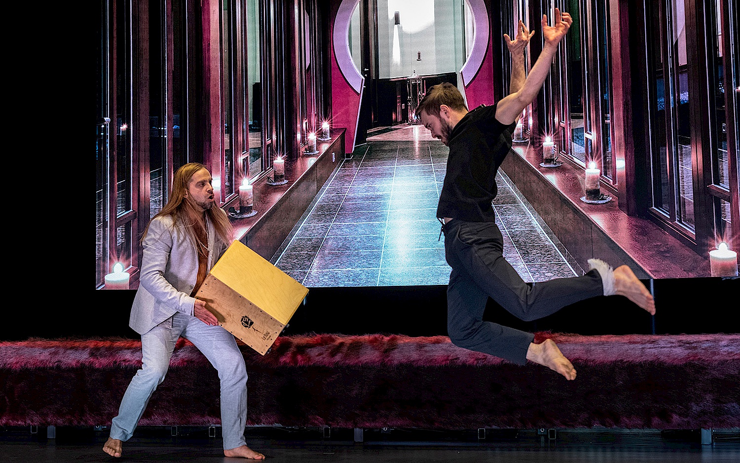 Falk Wenzel Zwei Performer vor Videoprojektion. Einer in schwarz gekleidet in der Sprungbewegung, einer in grau mit Cajon in den Händen.