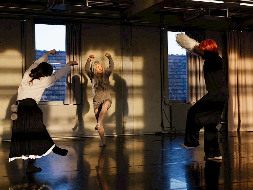 Three dancers in dynamic poses against a dark background