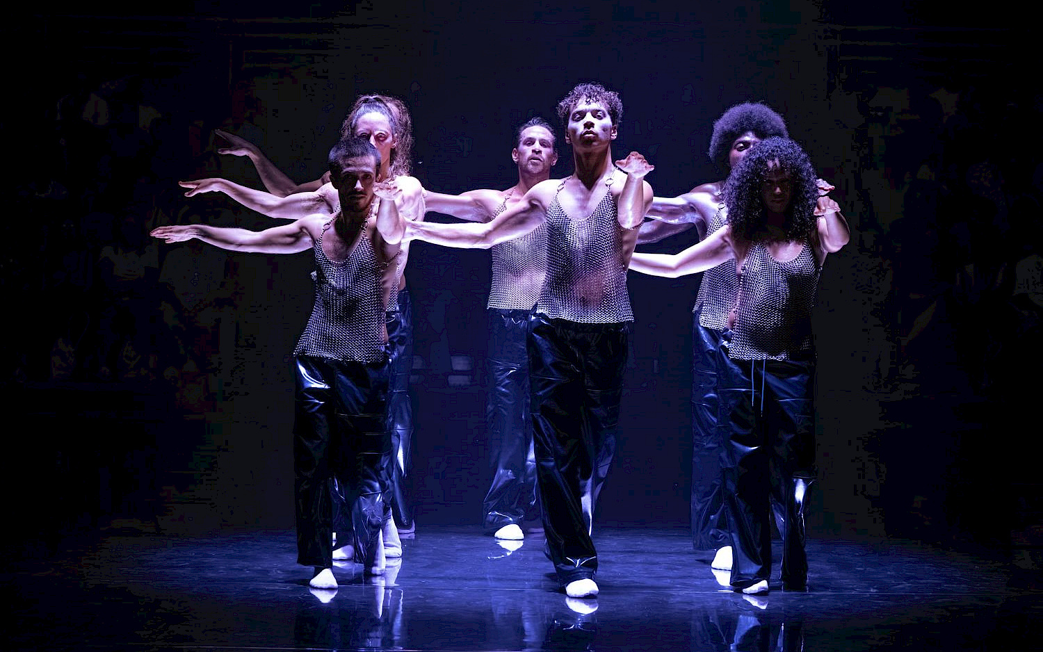 Blandine Soulage 6 Performer*innen in Kettenhemden auf einer bläulich beleuchteten Bühne.