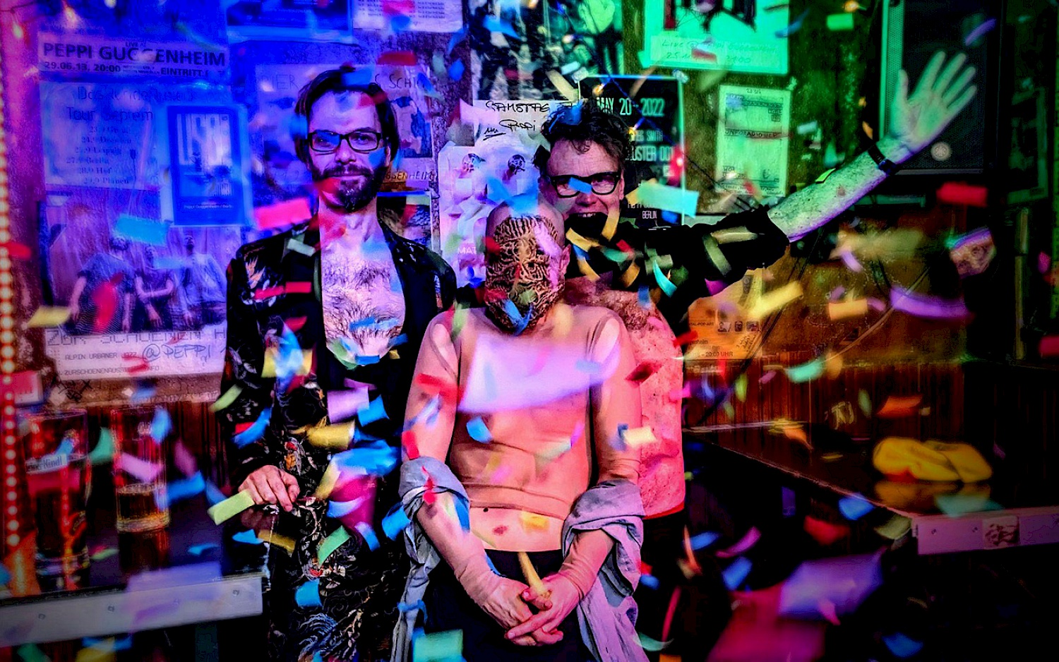 The members of the band **Y** Liz Kosack, Dan Peter Sundland and Steve Heather are surrounded by confetti and stand colorfully illuminated and in a good mood as a group