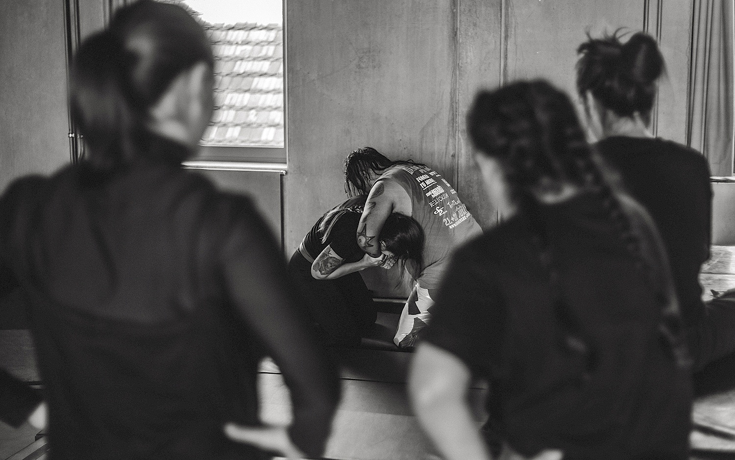 Three people in the foreground watch two people during a wrestling exercise in the Radialsystem studios. As part of Valeria Oviedo's residency