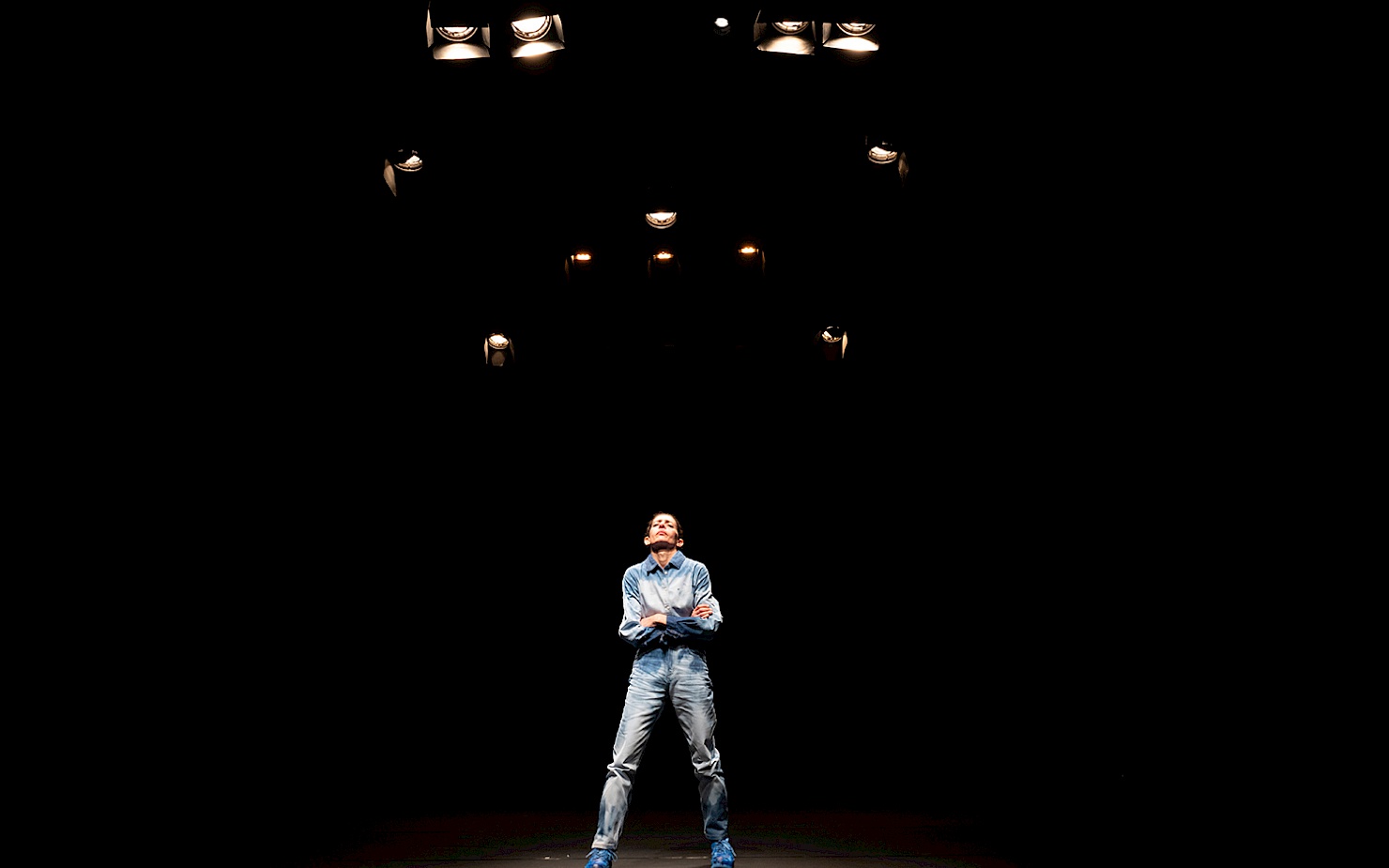 Beniamin Boar Maria Hassabi stands on an empty stage with her arms crossed and her head raised.